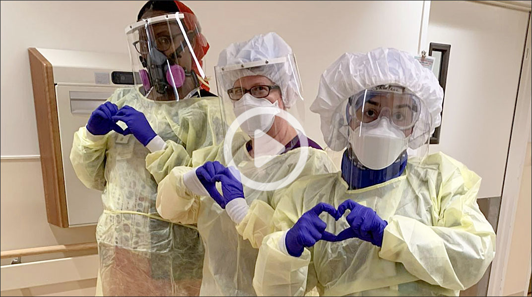 screenshot from video showing masked health workers making hearts